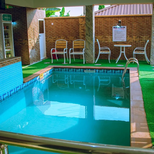 The hotel swimming pool with poolside chairs and a table